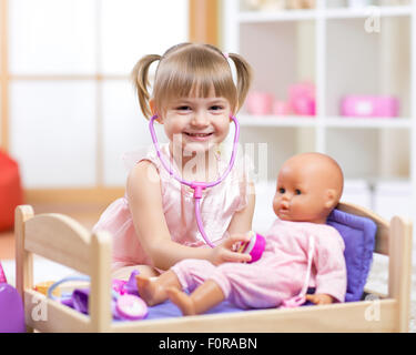 baby plays in doctor with toy doll and stethoscope Stock Photo