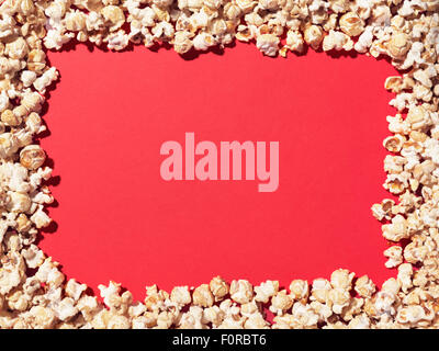 Shot of popcorn arranged to give a border to a plain, red area ideal for designer to add copy. Stock Photo
