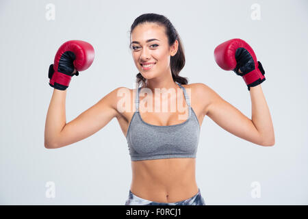 Portrait of a smiling fitness woman standing with boxing gloves in victory pose isolated on a white background Stock Photo