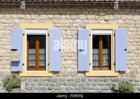 Lilac coloured shutters on the windows of an old French stone house in Normandy Stock Photo