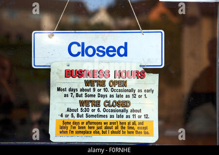 Amusing business hours notice hanging on a shop door in the west coast of Scotland village of Tarbert. Stock Photo