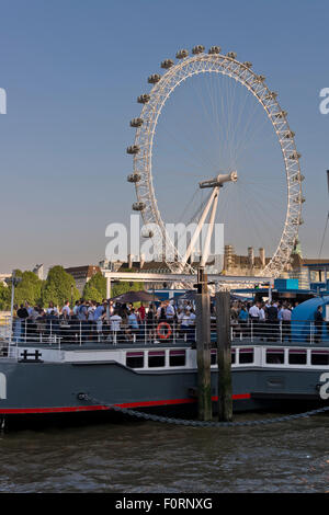 People aboard the Tattershall Castle, a floating bar on the River Thames with the London Eye in the background Stock Photo