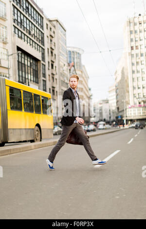 Businessman rushing across the road in a hurry Stock Photo