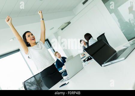 Businesswoman jumping from joy and raises both hands as a sign of success Stock Photo