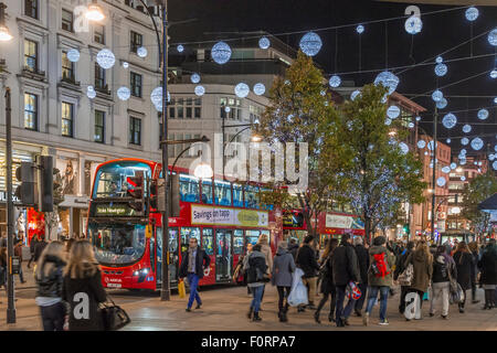 Buses passing beneath the Christmas lights on Oxford St, busy with Christmas shoppers ,at Christmas time, Oxford Street ,London, UK Stock Photo