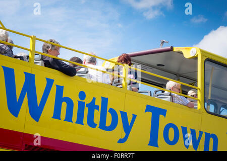A bright yellow open topped double decker bus which takes tourists on a tour around the seaside town of Whitby Stock Photo
