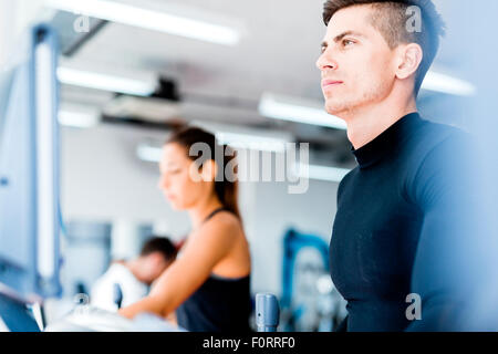Group of healthy young people using treadmill and elliptical trainer in a gym Stock Photo