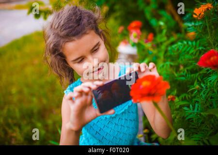 Teenage girl photographing flower phone on a green background in Stock Photo