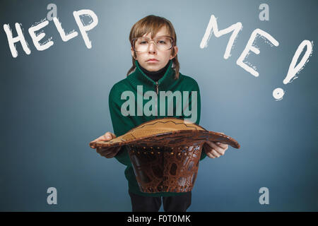 Teen boy homeless asking for help holding a hat inscription hel Stock Photo