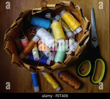 colored threads in a basket and scissors lying next Stock Photo