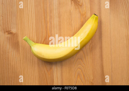 Single banana on wooden surface Stock Photo