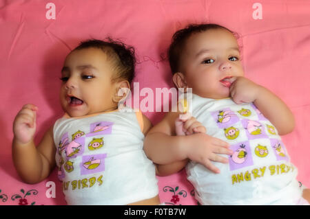 Portrait of twin baby brothers happily sharing a bed together and playing and smiling with copy space Stock Photo