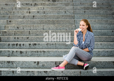 Healthy lifestyle  - teenager eating puffed bread outdoor sitting on stairs Stock Photo
