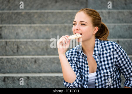 Healthy lifestyle  - teenager eating puffed bread outdoor sitting on stairs Stock Photo