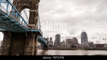 The Ohio River is at flood stage as it passes underneath a historical suspension bridge Stock Photo
