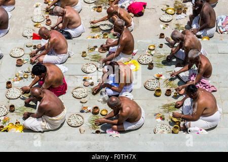 A group of male pilgrims is performing a pooja, a religious ceremony, in front of Badrinath Temple, one of the Dschar Dham Stock Photo