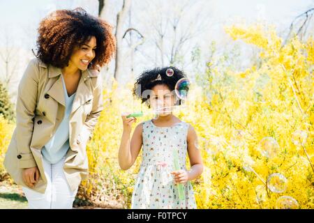 Front view of mother and daughter blowing bubbles