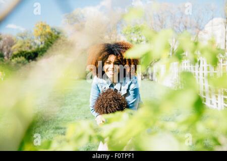 View through foliage of mother hugging daughter smiling Stock Photo