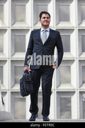 Full length front view of business man, hand in pocket, carrying briefcase Stock Photo