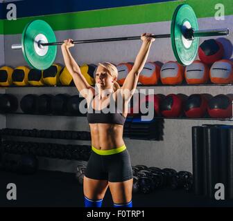 Young woman weight lifting with barbell in gym Stock Photo