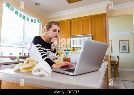 Woman using laptop in kitchen Stock Photo