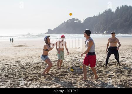 Four adult friends playing with ball on Short Sands Beach, Oregon, USA Stock Photo