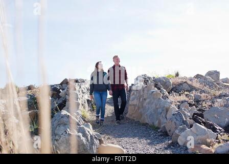 Full length front view of young couple holding hands walking, looking away Stock Photo