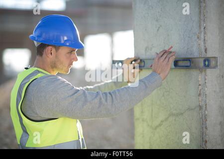 Surveyor using spirit level on construction site pillar Stock Photo