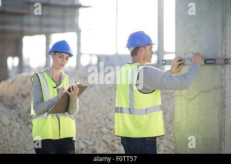 Builder using spirit level on construction site pillar Stock Photo
