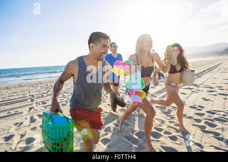 Group of friends running on beach, laughing Stock Photo