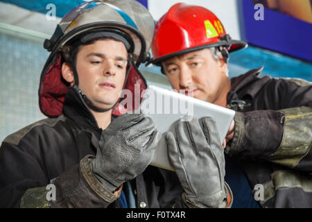 Male Firefighters Using Digital Tablet At Fire Station Stock Photo