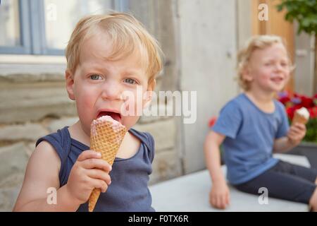 Two boys sitting outside eating icecream Stock Photo