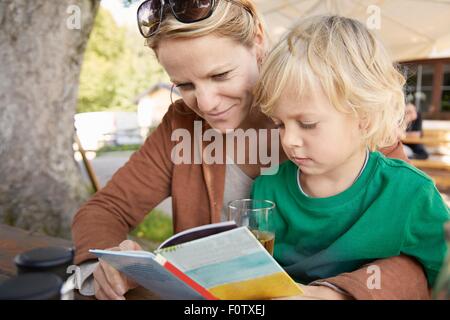 Mother and son reading book together, outdoors Stock Photo