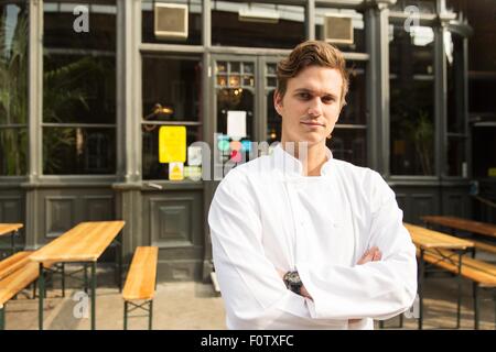 Young chef standing outside of work, arms folded Stock Photo