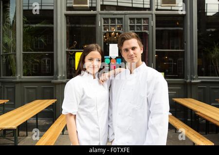 Couple in chef uniforms standing outside of work Stock Photo