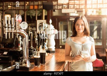 Mid adult woman working in public house holding chip and pin machine Stock Photo