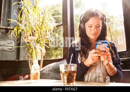 Mid adult woman wearing earphones using smartphone Stock Photo