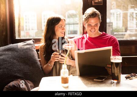 Couple enjoying drinks looking at newspaper together Stock Photo