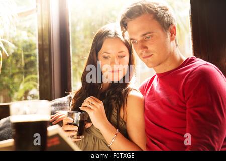 Couple sitting having a drink together reading newspaper Stock Photo