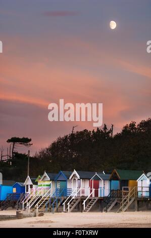 Row of multi-colored beach huts in moonlight, Norfolk England, UK Stock Photo