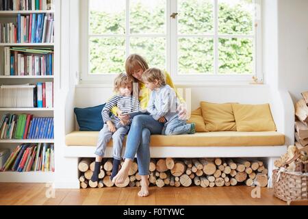 Mother and two sons, sitting in window seat, looking at digital tablet Stock Photo