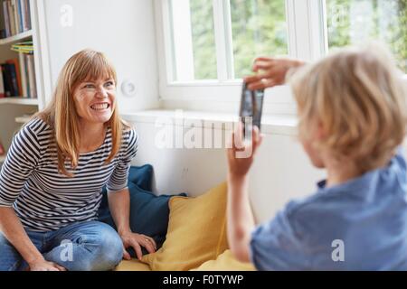 Young boy taking photograph of mother, using smartphone Stock Photo