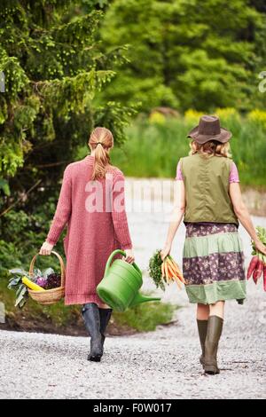 Rear view of two women carrying vegetables Stock Photo