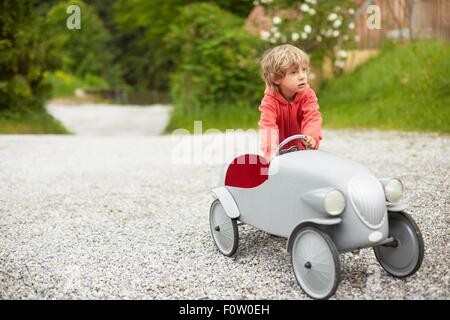 Boy playing with vintage toy car outdoors, looking away Stock Photo