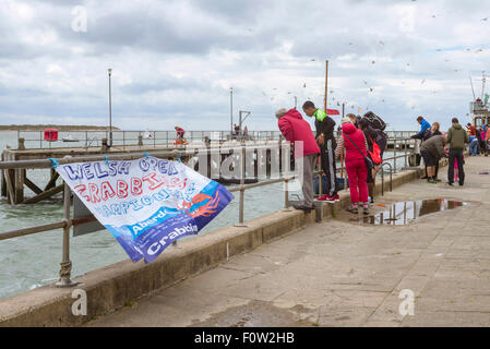 Families gather at the quayside to watch or participate in the Welsh open crabbing championship in Aberdyfi Wales. Stock Photo