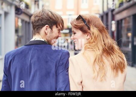 Rear view of couple strolling along street, London, UK