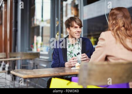 Over shoulder view of couple chatting at sidewalk cafe, London, UK Stock Photo