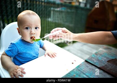 Father feeding son in high chair Stock Photo