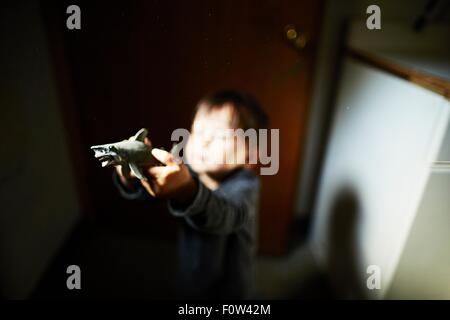 Boy holding up toy shark in kitchen Stock Photo