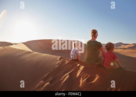 Mother and sons sitting on sand dune, Namib Naukluft National Park, Namib Desert, Sossusvlei, Dead Vlei, Africa Stock Photo